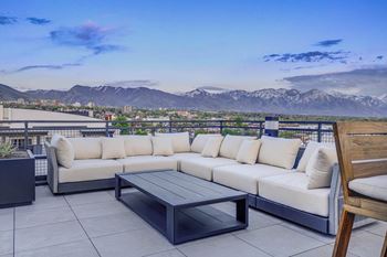 a patio with couches and a table on a balcony overlooking the mountains